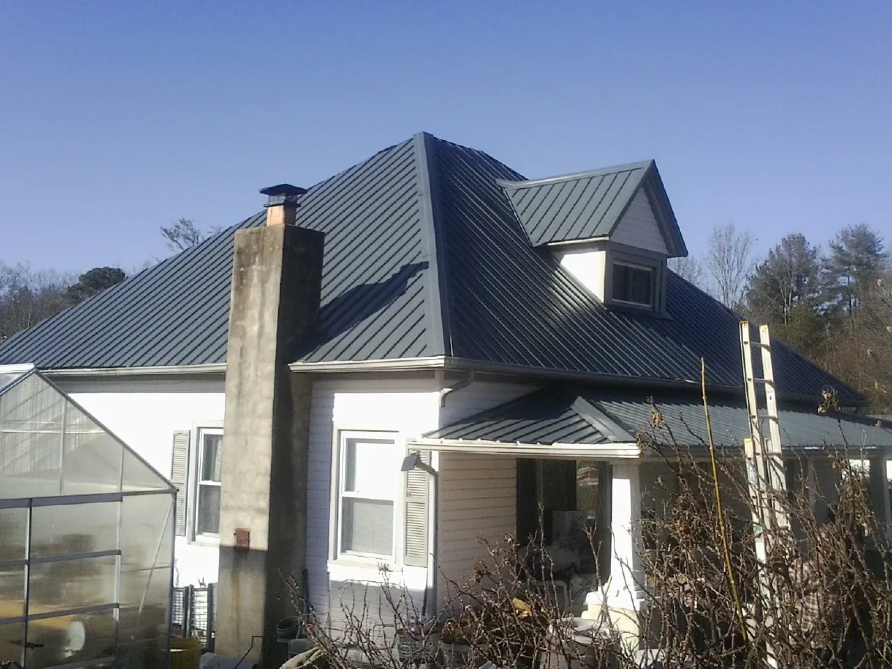 Dark blue standing seam metal roof on a white farmhouse with dormer — Slate & Tile Roof Repair by Roofing Brothers in Woolford