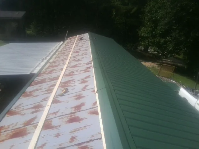 Old rusted panels beside newly installed green metal roofing — Wind Damage Roof Repair by Roofing Brothers in Woolford