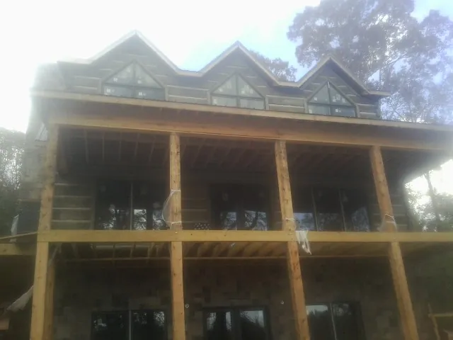 Dormers and porch framing on a large log home under construction — Roof Coating work by our crew in Woolford