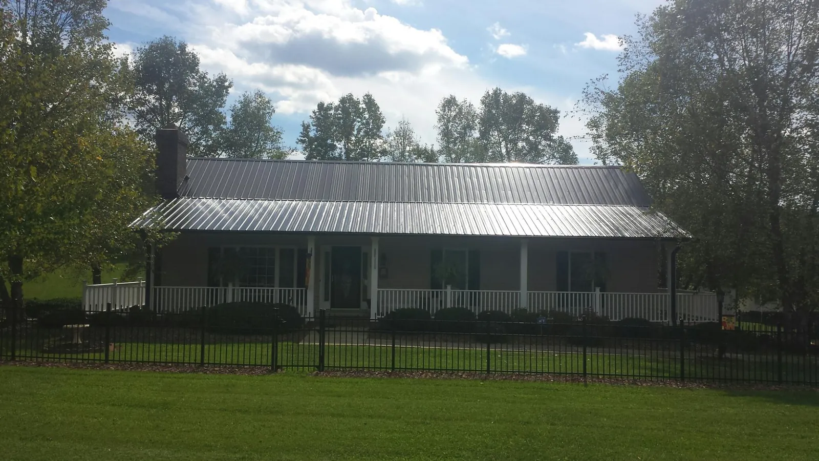 Gray metal roof on a brick ranch with a full width front porch — Gutter Guard Installation work by our crew in Woolford